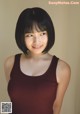 A woman in a red tank top posing for a picture.