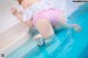 A woman in a pink and white bathing suit laying on the edge of a pool.