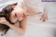 A woman laying on a bed in a white lingerie.