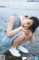 A young woman sitting on the edge of a body of water.