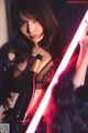 A woman holding a bottle of wine and a light saber.